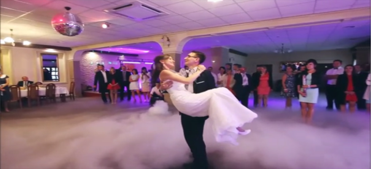 A wedding couple performing a dramatic ballroom dance lift during their first dance