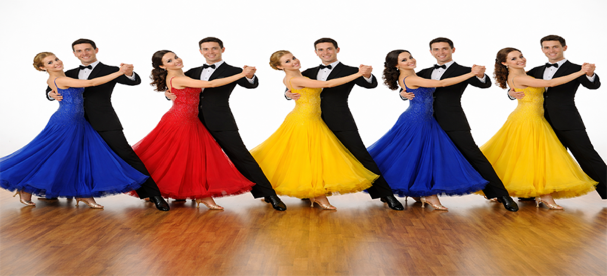 A multi‑age group of dancers smiling on stage during a lively performance
